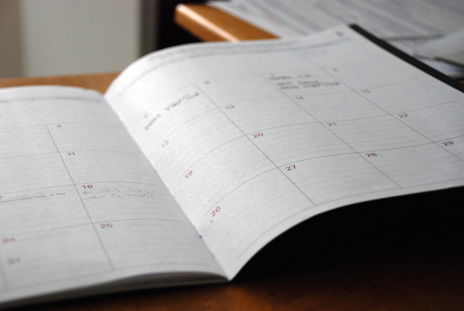 An open monthly planner on a wooden desk